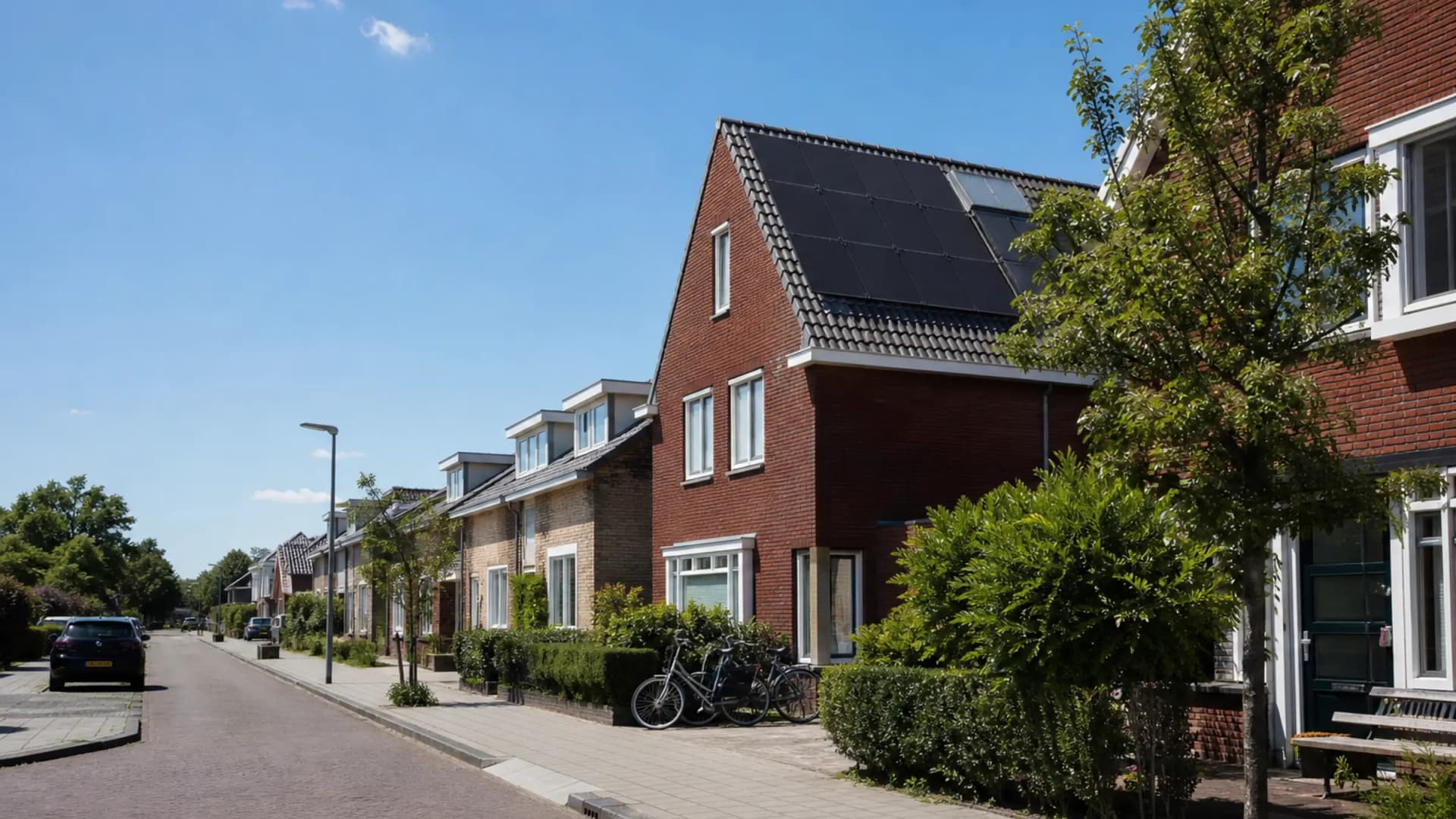 Rustige Nederlandse woonwijk met zonnepanelen op een rijtjeswoning onder een blauwe middaghemel